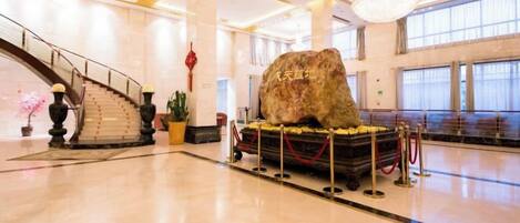 A spacious lobby with a grand staircase, a large rock sculpture, and a chandelier.