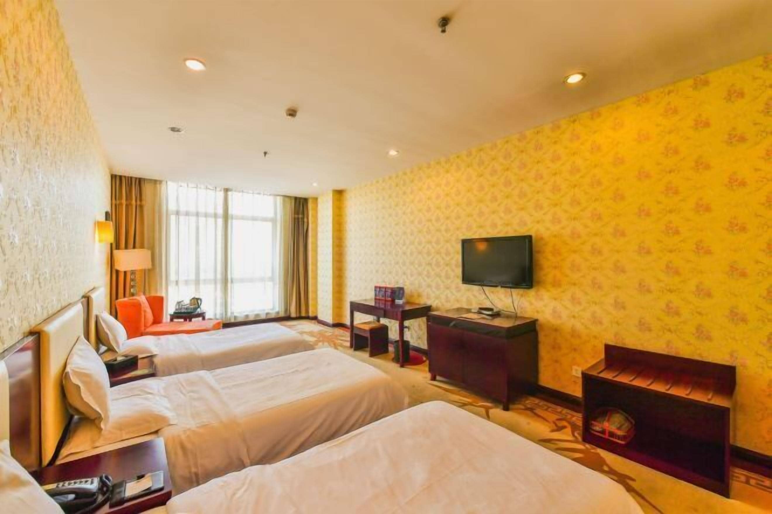 Una habitación de hotel con dos camas, televisión, escritorio y un pequeño rincón de descanso.