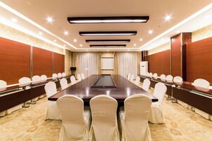 A conference room with a long table, white chairs, and a carpeted floor.