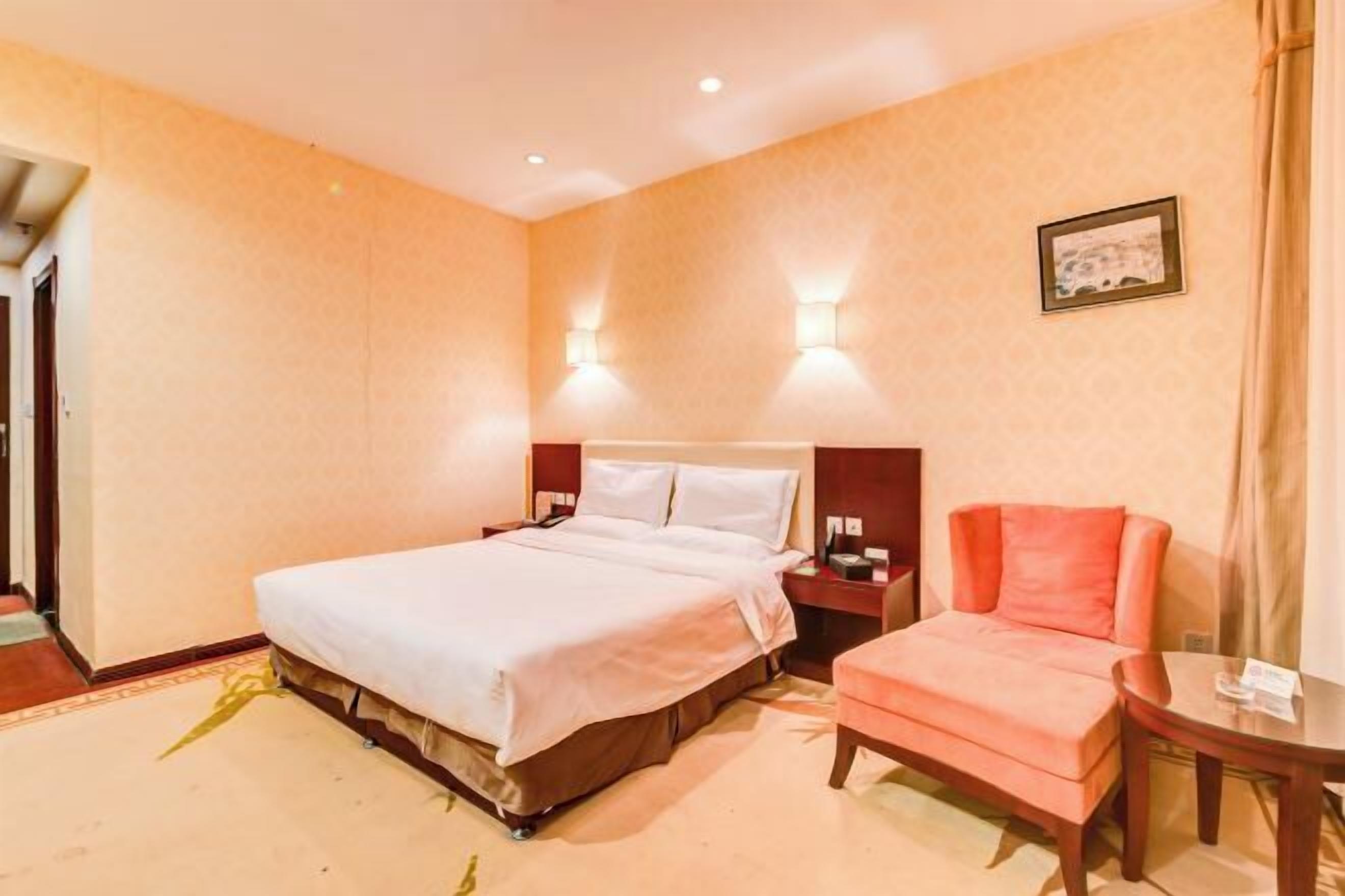 A hotel room with a bed, a nightstand, a chair, and a small table.