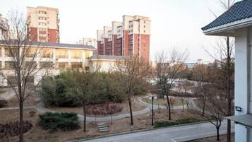 A residential area with a paved walkway, trees, and multi-story buildings in the background.