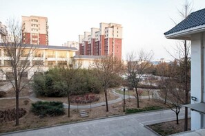 A residential area with a paved walkway, trees, and multi-story buildings in the background. - Yu Jing Lou Hotel (Ci County)
