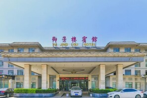 A hotel entrance with a sign in a foreign language, a covered walkway, and a few cars parked in front. - Yu Jing Lou Hotel (Ci County)