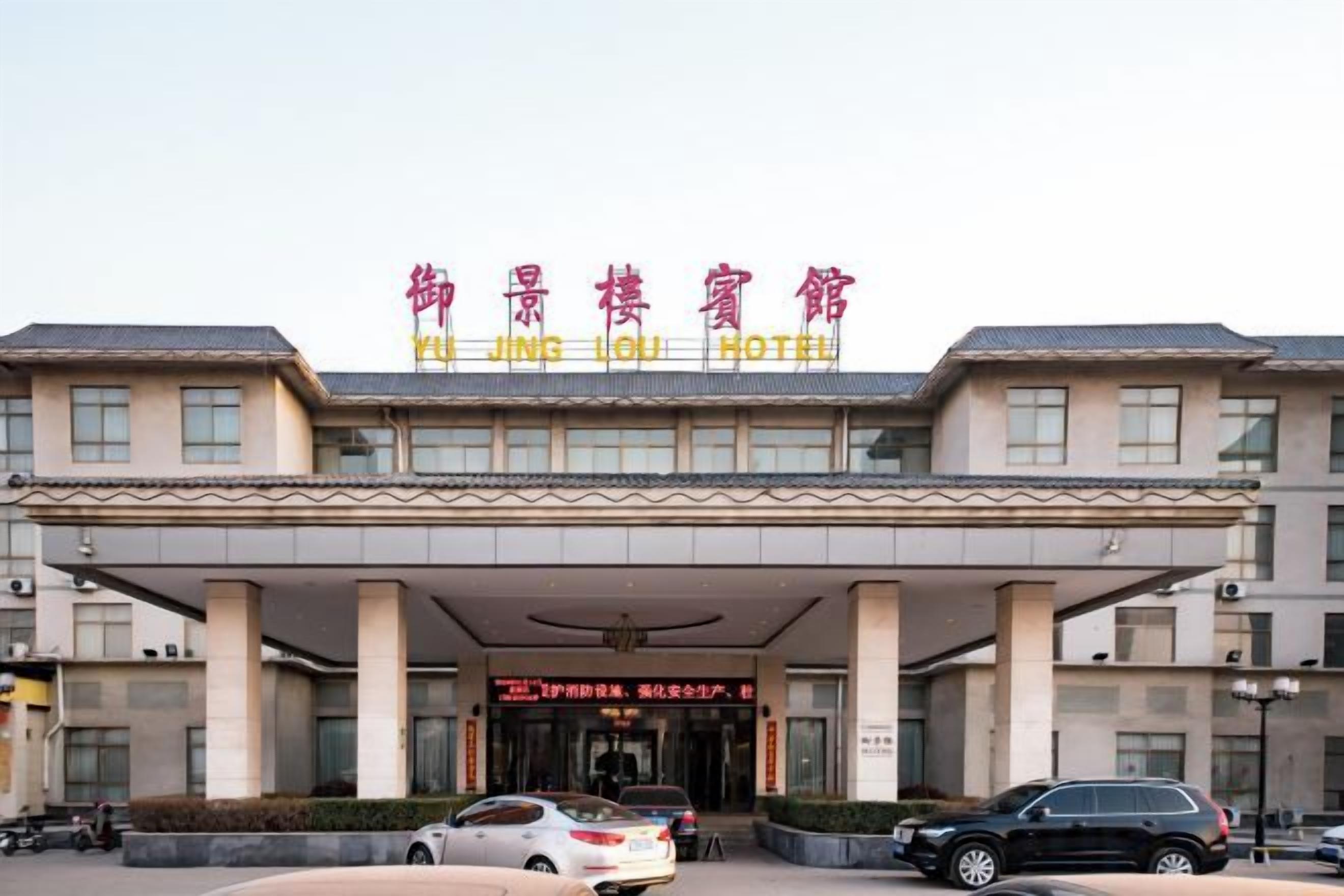 A hotel with a covered entrance, multiple columns, and a sign in a foreign language.