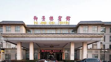 A hotel with a covered entrance, multiple columns, and a sign in a foreign language.