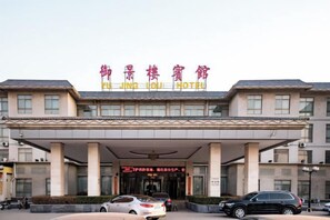 A hotel with a covered entrance, multiple columns, and a sign in a foreign language. - Yu Jing Lou Hotel (Ci County)