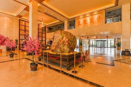 A lobby with a large rock centerpiece, potted plants, and a traditional Chinese mural.. Yu Jing Lou Hotel