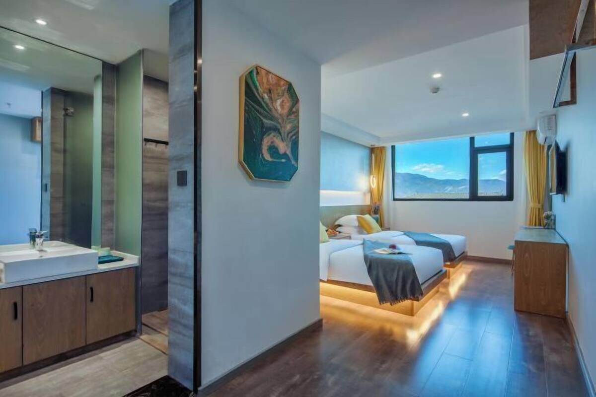Un hotel moderno con una cama grande, un baño con espejo y lavamanos, y vistas a las montañas.