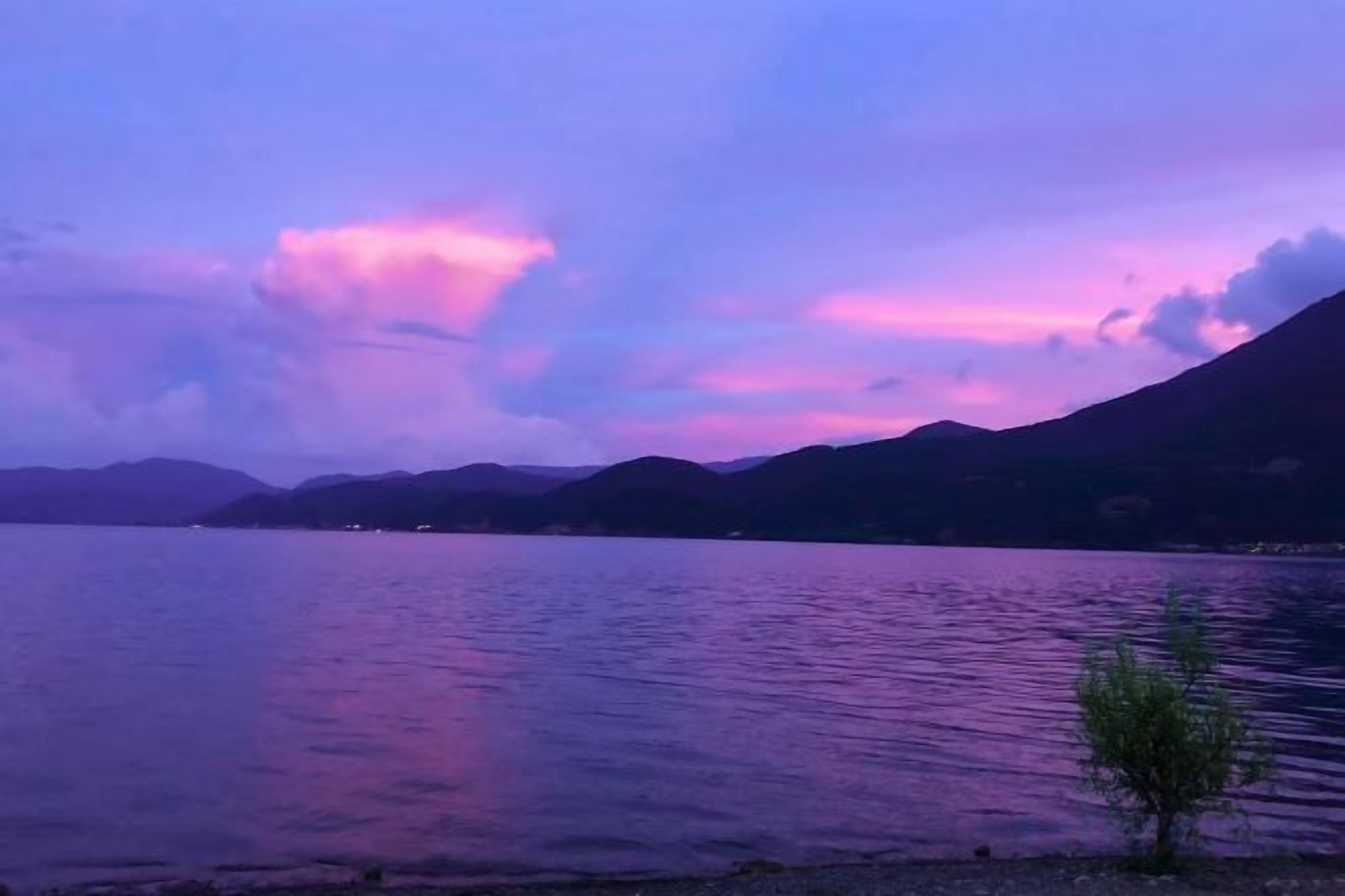 Un lago tranquillo con montagne sullo sfondo e un cielo sereno.