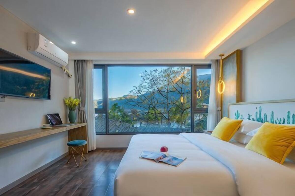 Una habitación de hotel moderna con una cama grande, un escritorio y vistas a las montañas.