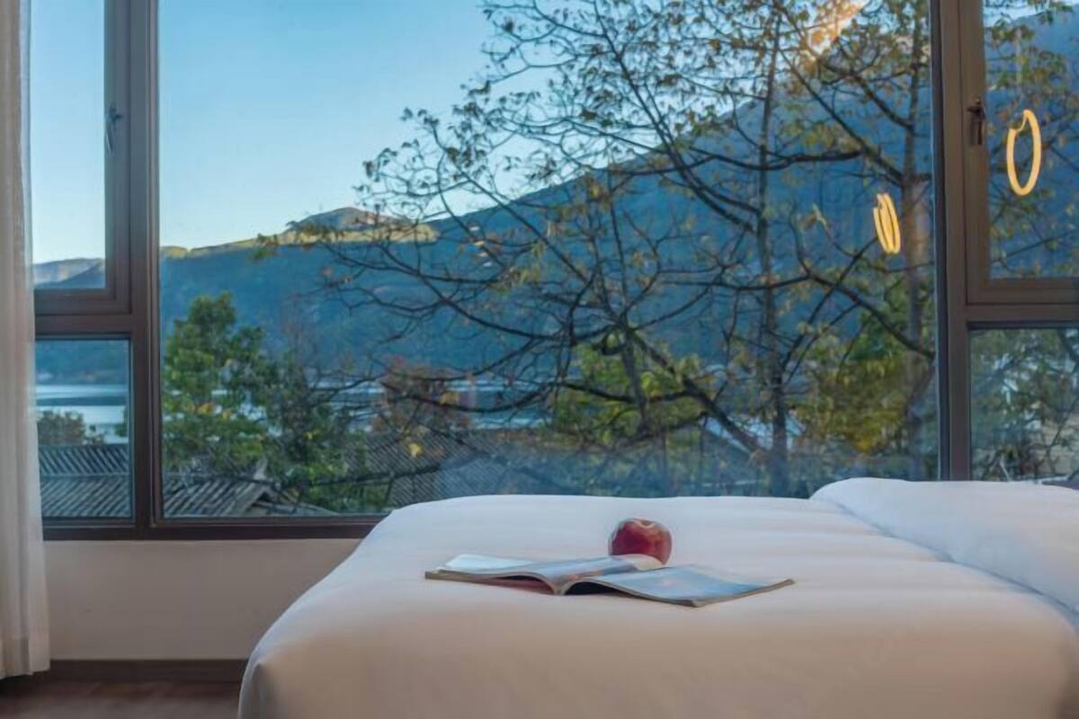Un dormitorio con una ventana grande, una cama y un libro.