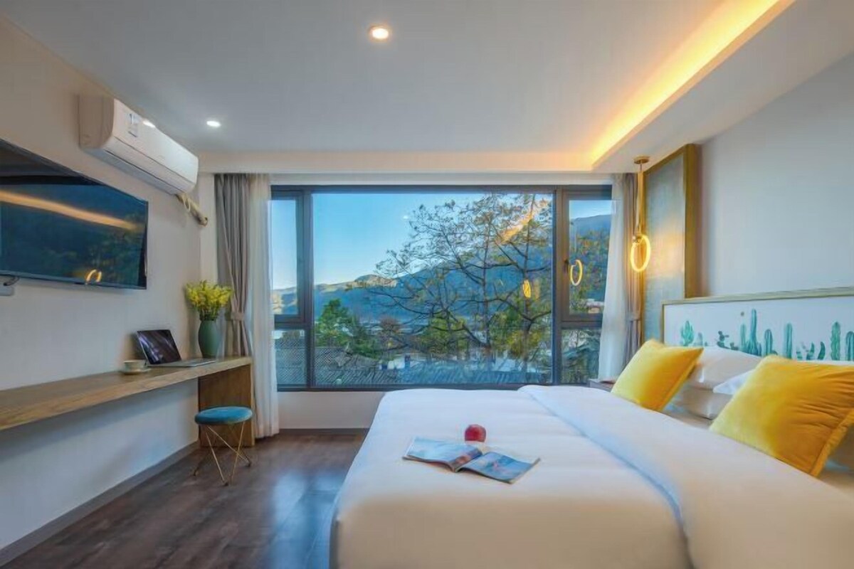 Una habitación de hotel moderna con un ventanal grande, una cama, un escritorio y una silla.