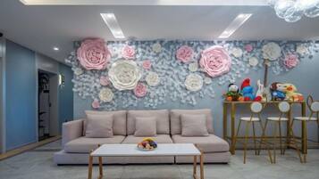 A living room with a sofa, a coffee table, and a wall decorated with floral patterns.