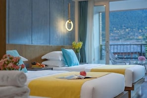 Une chambre d’hôtel avec deux lits, un balcon offrant une vue agréable et un décor moderne.