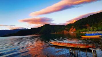A calm lake with boats, a dock, and a mountainous backdrop.