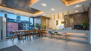 A modern hotel lobby with a reception desk, seating area, and large windows offering a view of the outside. - Lugu Lake Yueji Hotel (Ninglang)
