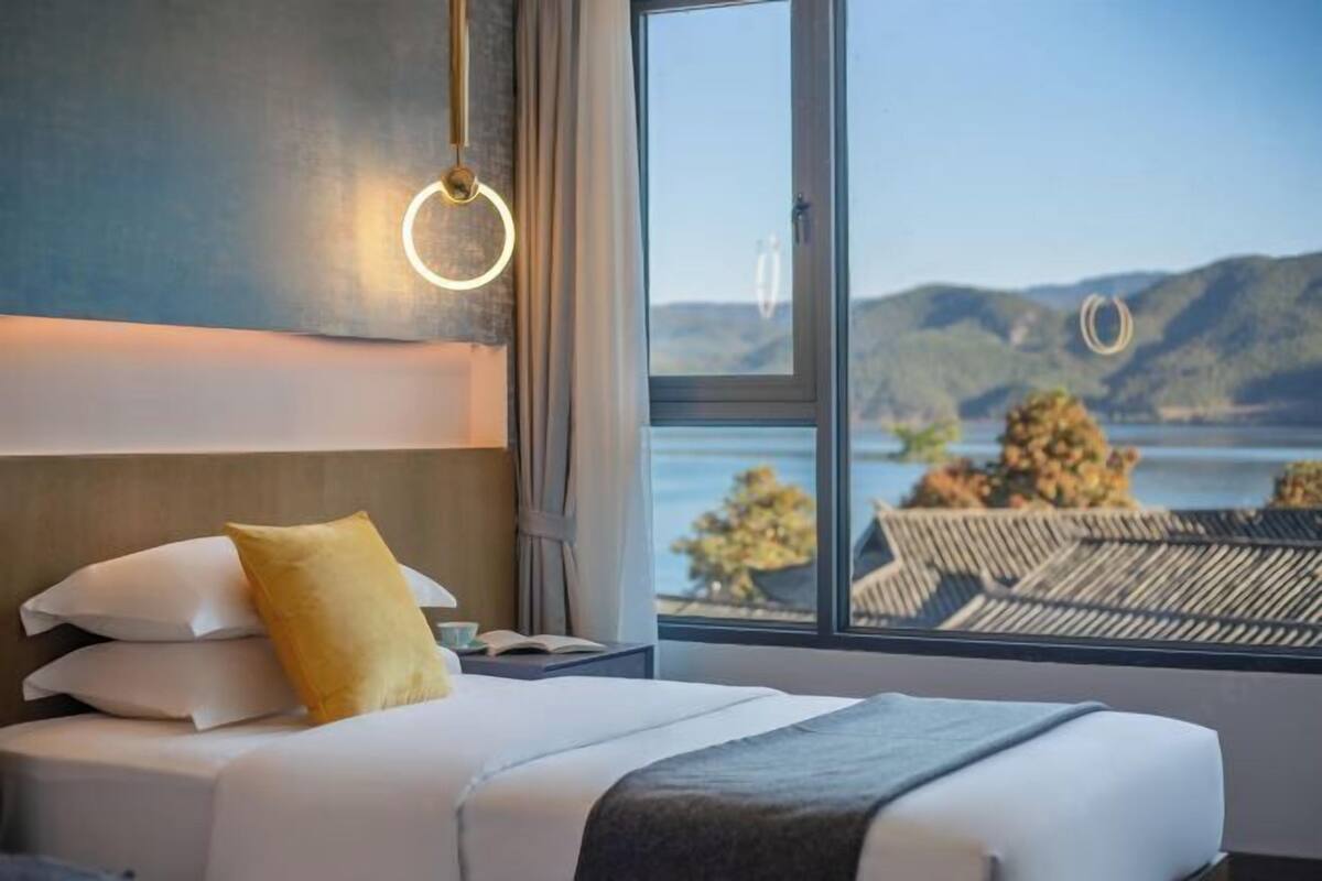 Una habitación de hotel con cama, vistas al exterior y una ventana con cortinas.