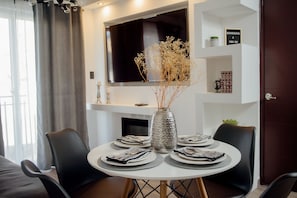 A dining area with a round table set for four, a vase with dried flowers, and a flat-screen TV mounted above. - Modern apartment, 5 min from the central park! (Quezaltenango)