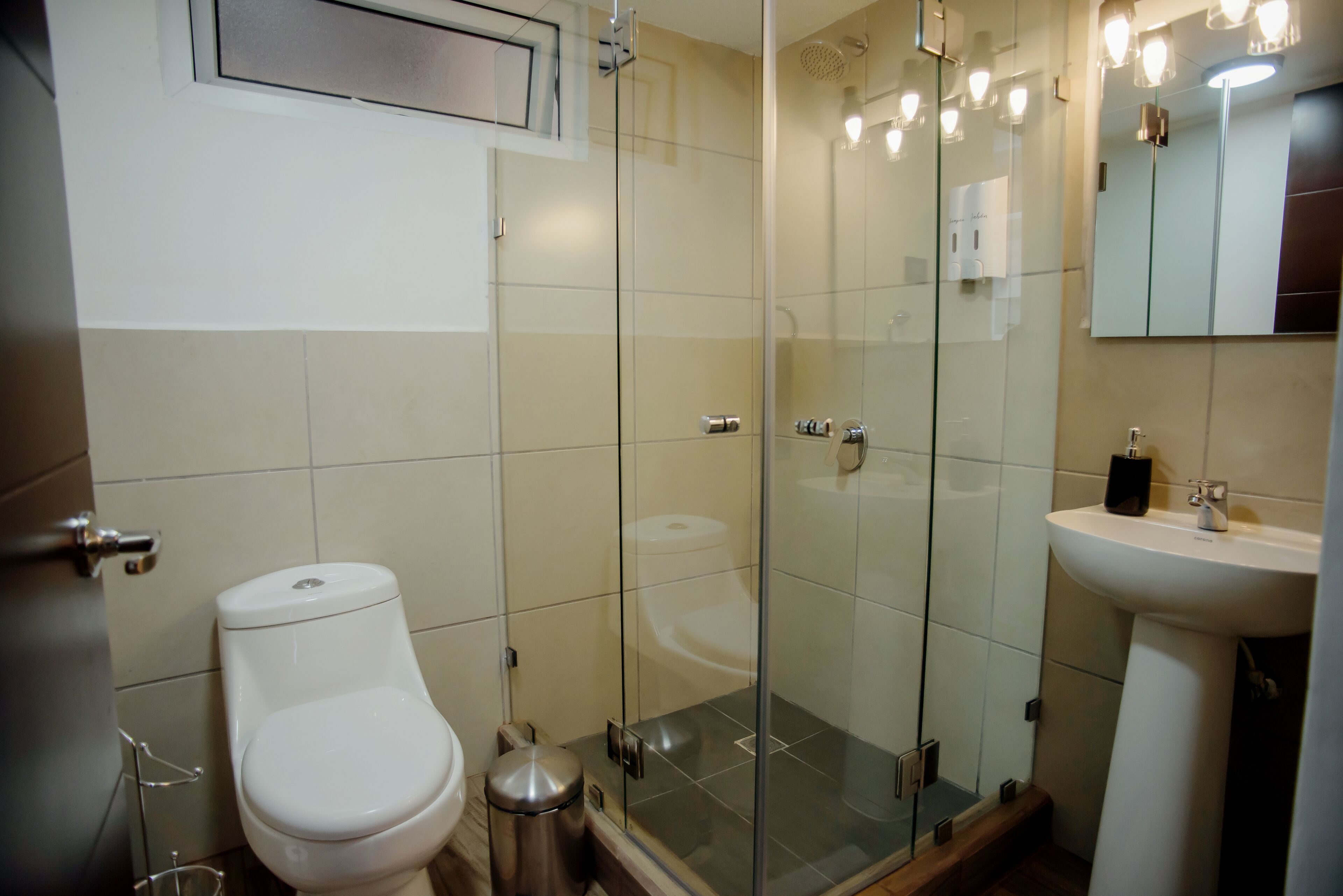 A modern bathroom with a toilet, glass shower enclosure, and a sink.