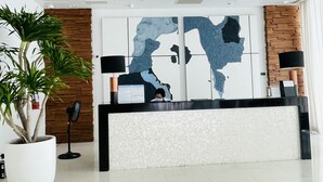 Een modern receptiegedeelte met een groot kunstwerk van een kaart, een receptiebalie, een potplant en een houten accentmuur.