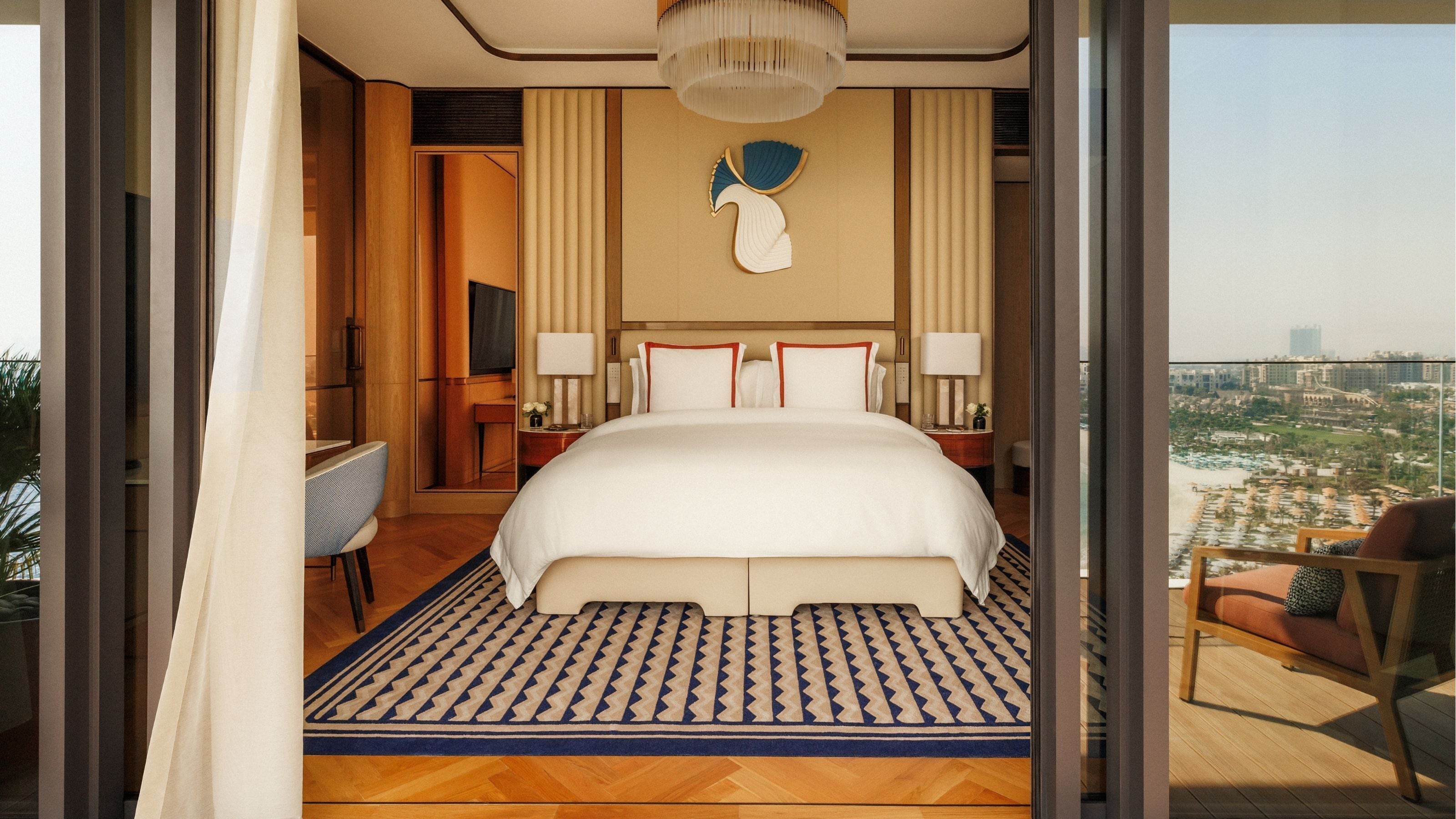 A spacious hotel room with a large bed, a desk, and a view of the city.