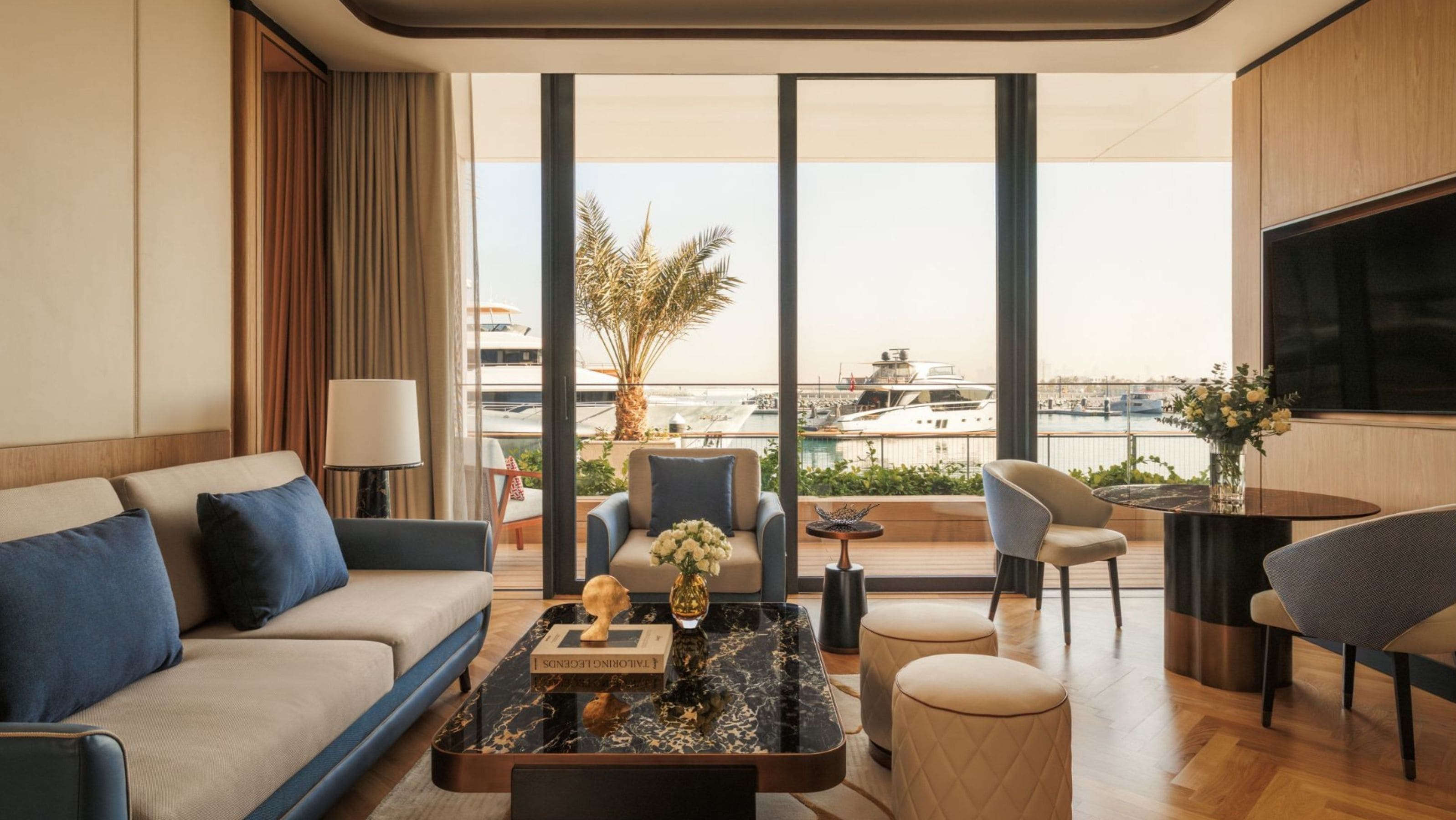 Une chambre d’hôtel moderne dotée d’un grand balcon, d’un canapé, d’une table basse et d’un téléviseur.