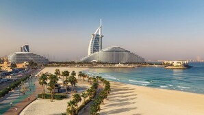 A coastal resort with modern architecture, including a distinctive sail-shaped building, a beach promenade, and a marina. - Jumeirah Residences Marsa Al Arab (Dubai)