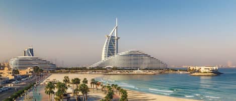 A coastal resort with modern architecture, including a distinctive sail-shaped building, a beach promenade, and a marina.