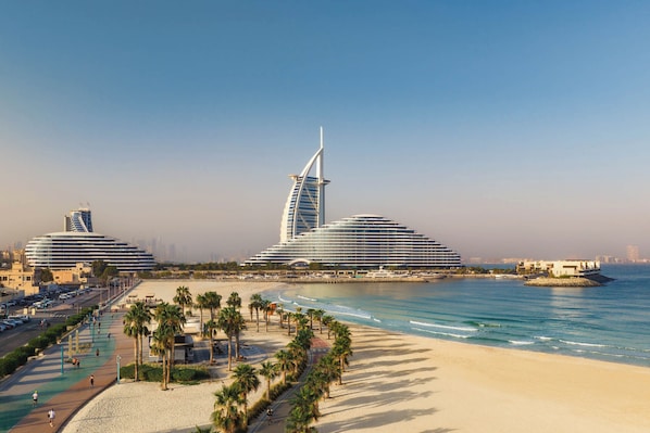 Um resort costeiro com arquitetura moderna, incluindo um edifício com formato de vela, um calçadão à beira-mar e um porto de iates.