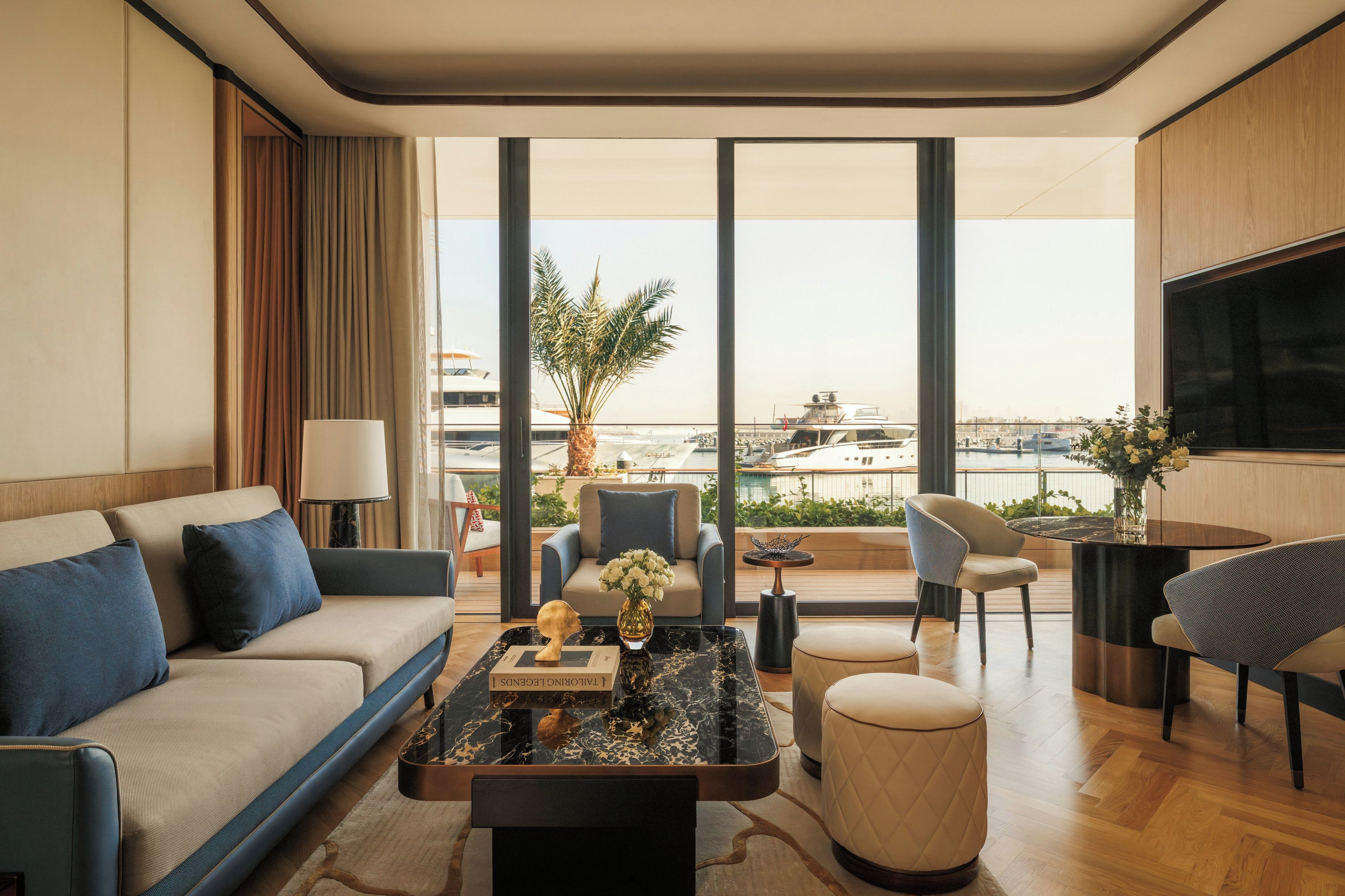 A modern hotel room with a sofa, armchair, coffee table, and a view of the sea.