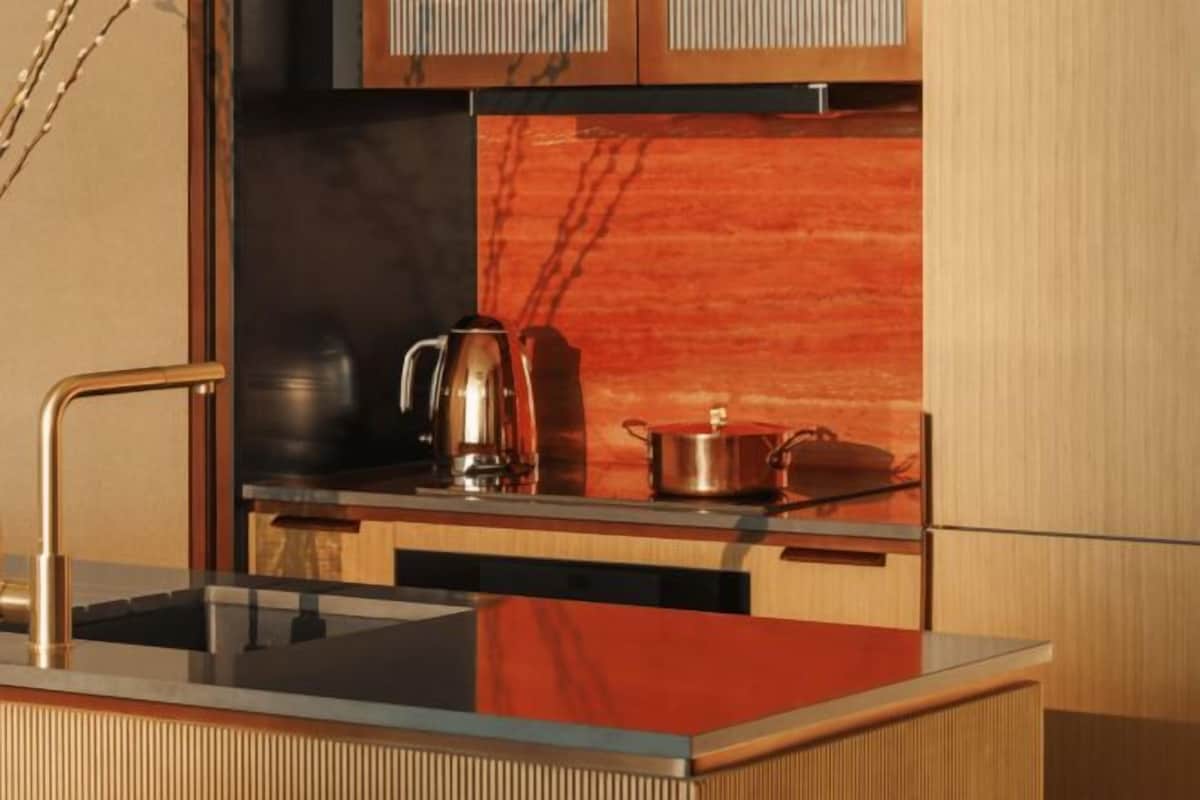 A modern kitchen with a stainless steel sink, a coffee maker, and a kettle on the countertop.