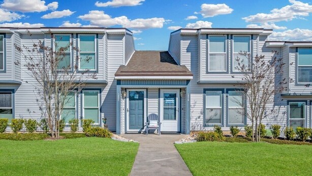 A row of modern, two-story townhouses with a central entrance and a covered walkway. - Walk to beach. Perfect for families & couples. Pool & tennis onsite. (Fernandina Beach)