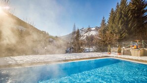 A pool with clear blue water, surrounded by snow-covered ground and trees. - Ferienwohnung in Viehofen (Viehofen)