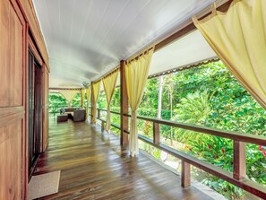 A wooden deck with a covered area, featuring a sofa and a fan. - Casa Creole - Private, Secure, Steps from the Beach (Cahuita)