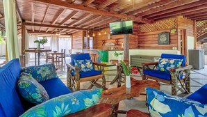 Ein Holzinterieur mit Barbereich, Sitzgelegenheiten mit floralen Kissen und einem an der Wand montierten Fernseher.