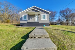 Ein Bungalow mit Veranda, Betonauffahrt und Rasen.