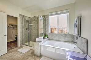 Une salle de bain moderne dotée d’une douche à parois de verre, d’une grande baignoire et d’un dressing.