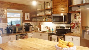 Una cucina con mobili in legno, un forno a microonde, un fornello e un frigorifero.