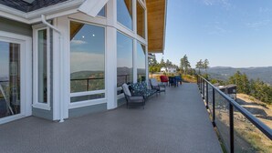 Un edificio moderno con ventanas amplias y un balcón con vistas a un paisaje montañoso.