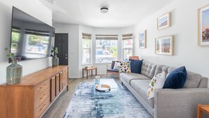 A modern living room with a wooden cabinet, a glass coffee table, a grey sofa, and a blue rug. - //The Tag House// 5 minutes to BSU, airport, hiking and downtown (Boise)