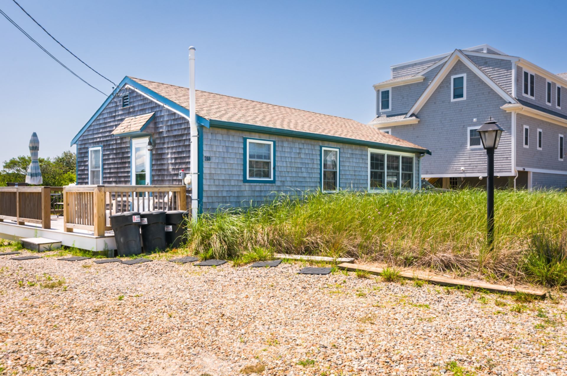 Une maison à deux étages avec une façade bleue et une terrasse en bois.