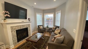 Un salon avec une cheminée, un canapé, une table basse et un téléviseur fixé au-dessus de la cheminée.