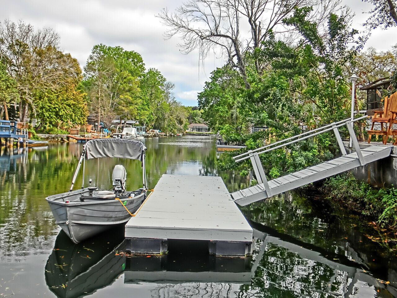 A narrow waterway with a dock, a small boat, and a pedestrian bridge.