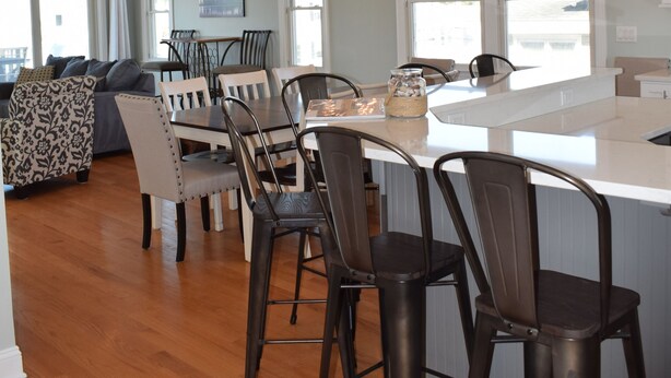 A modern kitchen with a central island, bar stools, and pendant lighting. - Oceanside open concept home, roof deck with ocean and sunset bay views, firepit! (Beach Haven Crest)
