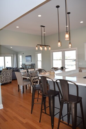 A modern kitchen with a central island, bar stools, and pendant lighting. - Oceanside open concept home, roof deck with ocean and sunset bay views, firepit! (Beach Haven Crest)