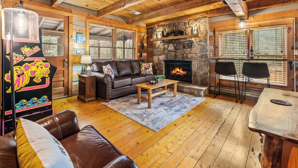 Un interior acogedor de cabaña con chimenea de piedra, muebles de cuero y pisos de madera.