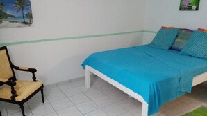 Un dormitorio con cama, una silla y una alfombra pequeña.