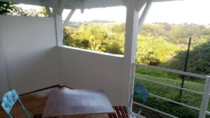 Un balcón con mesa y sillas, con vistas a un paisaje verde.