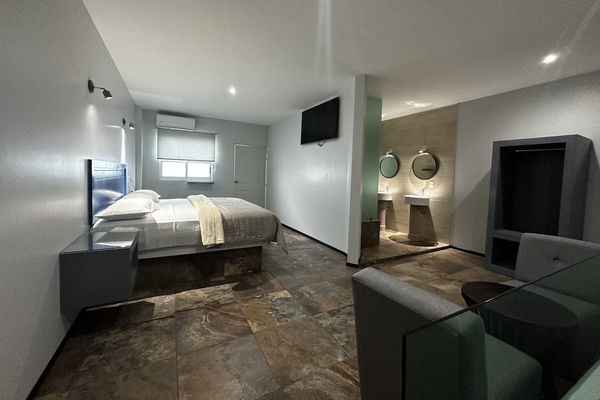 A modern bedroom with a bed, bedside table, and a TV mounted on the wall.