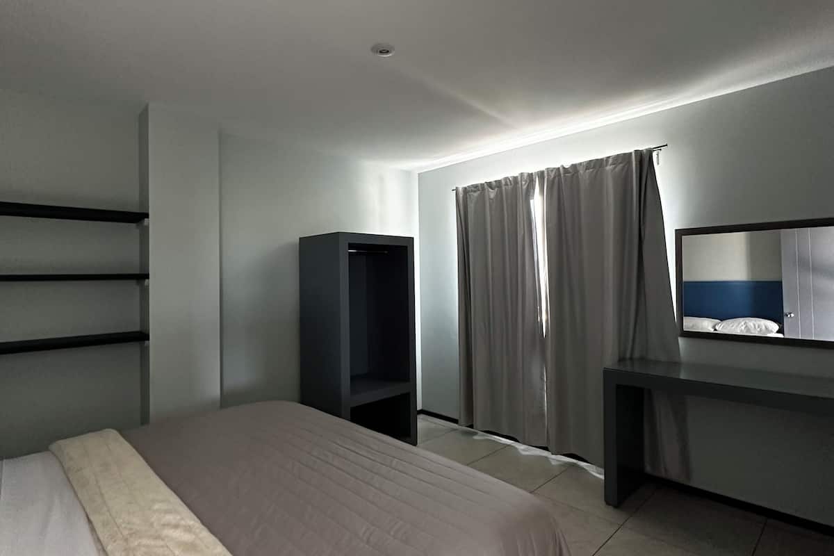 A modern hotel room with a large bed, a desk, a TV, and a wardrobe.